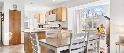 A modern kitchen with wooden cabinets, a central island, and a dining area with a table and chairs.