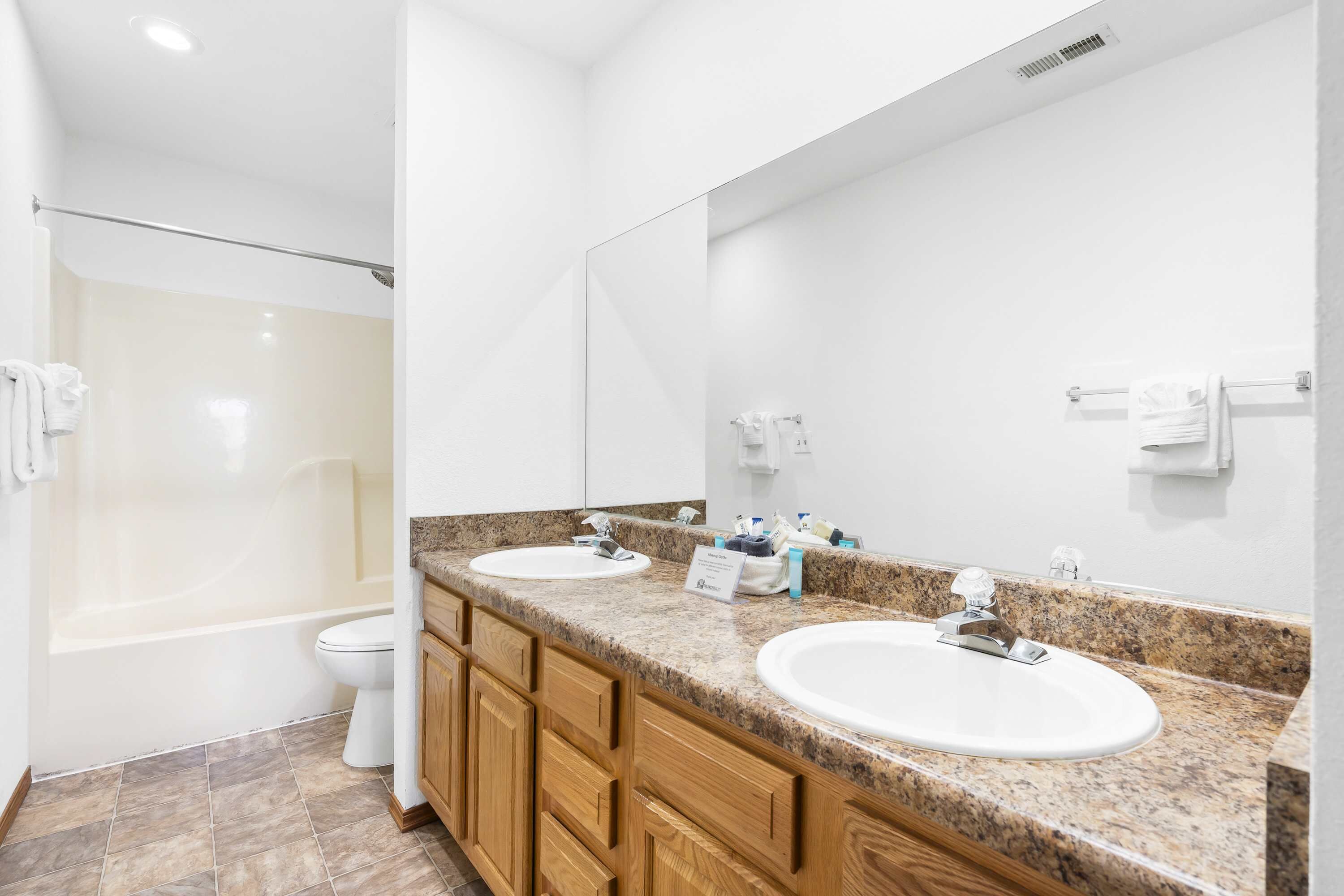 A modern bathroom with two sinks, a large mirror, and a shower area.