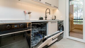 A modern kitchen with a dishwasher, oven, and a built-in washing machine. - Stunning 2 bedroom apartment in Herdade da Aroeira (Almada)