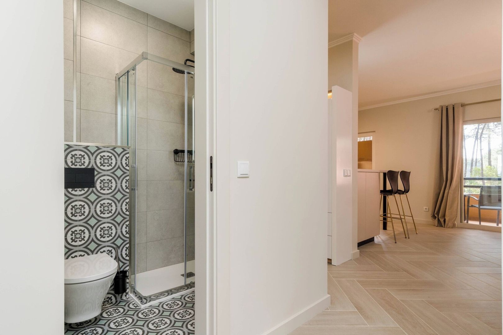 A modern bathroom with a shower, toilet, and patterned floor tiles.