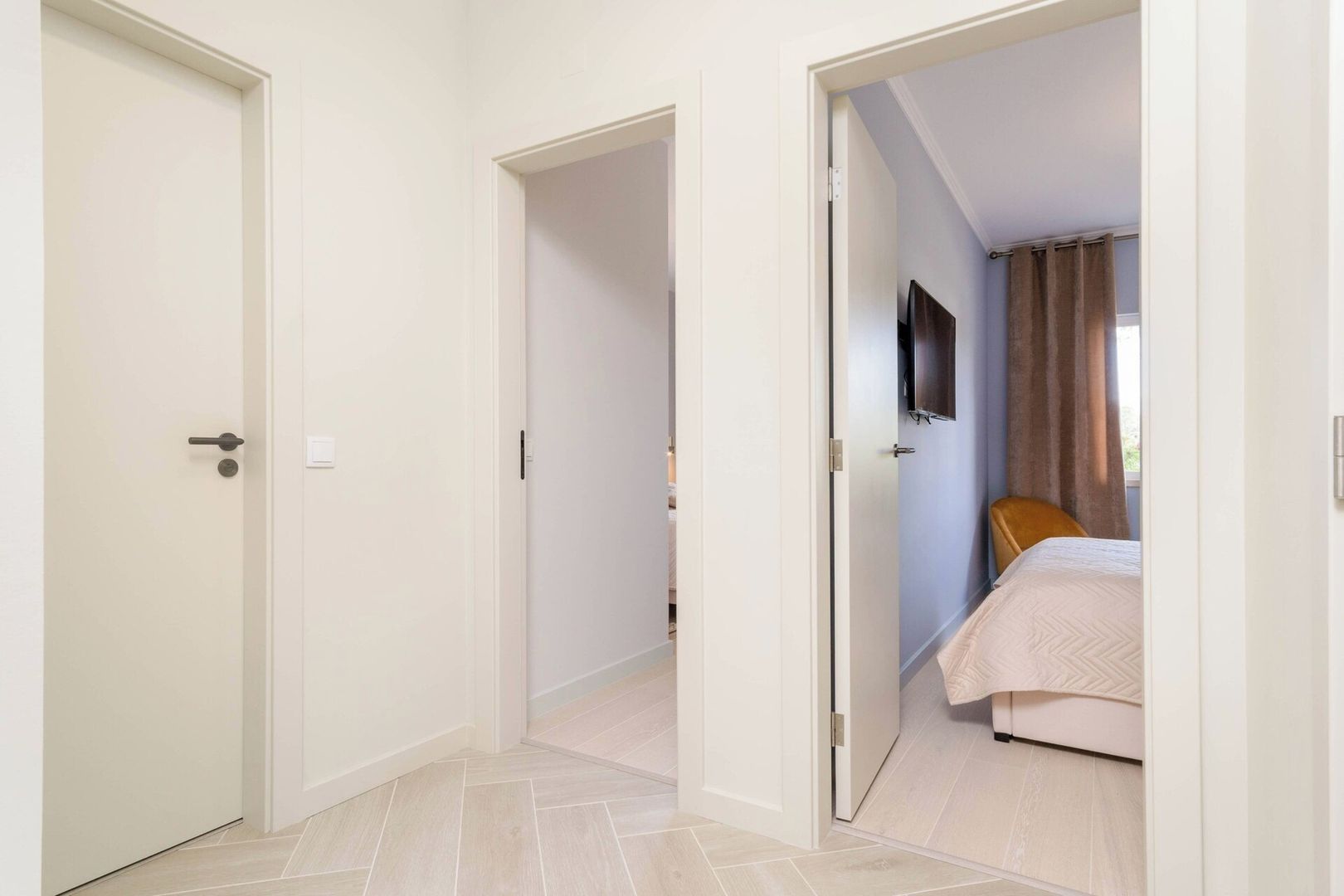 A hotel room with a bed, a television, and a door leading to another room.