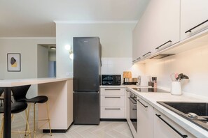 Una cocina moderna con un refrigerador de acero inoxidable, un microondas y una cafetera.