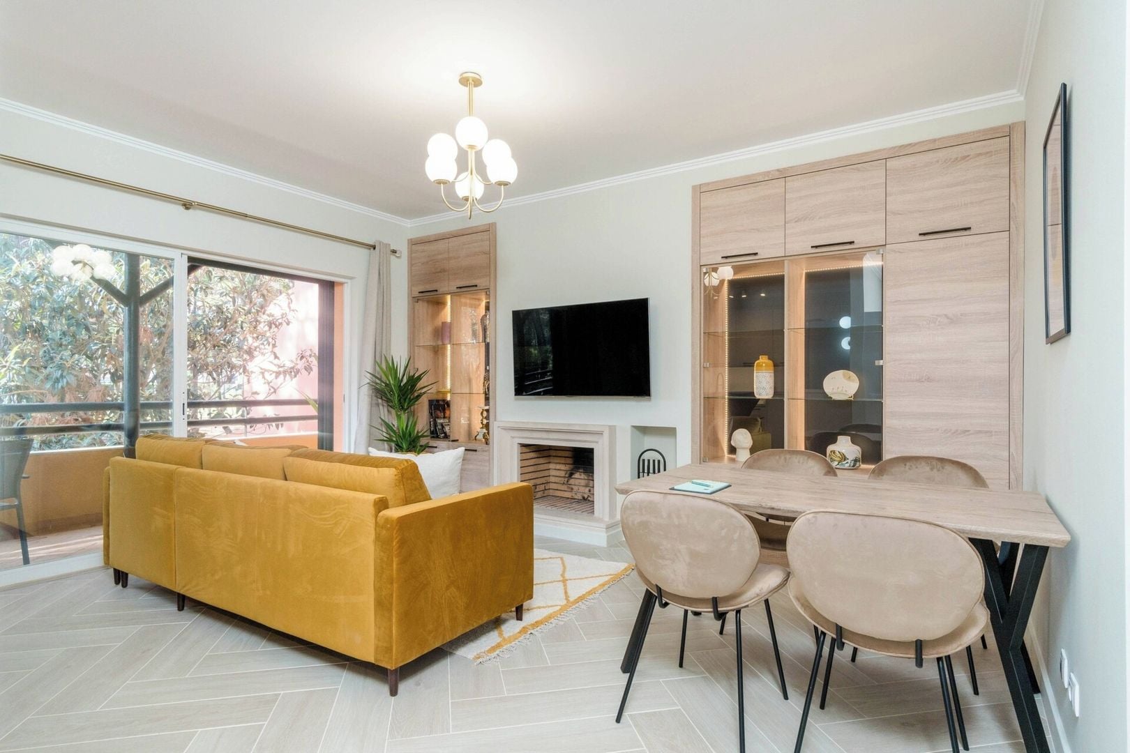 Una sala de estar moderna con sofá, mesa de comedor, sillas, televisor de pantalla plana y chimenea.