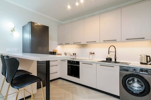 A modern kitchen with a built-in oven, dishwasher, and washing machine.