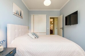 Ein Schlafzimmer mit einem großen Bett, einem Fernseher an der Wand und einem Gemälde über dem Bett.