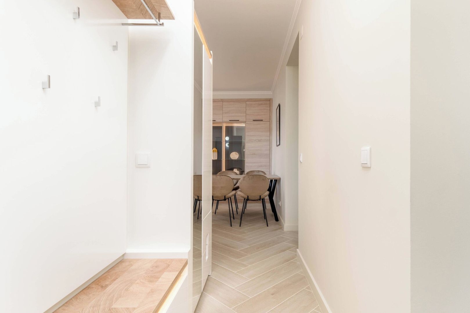 Un couloir qui se termine par un espace repas, comprenant une table et des chaises.