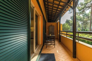 Ein Balkon mit Tisch, Stühlen, einer Tür und Blick auf Bäume.