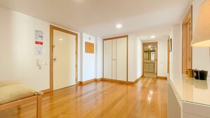 A hallway with wooden flooring, white walls, and a door with a small wooden panel. - Poolside Bliss T1 Hsrentals Vilamarina (Loulé)