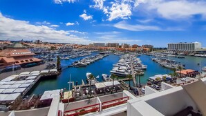 Un puerto deportivo con numerosas embarcaciones amarradas, un cielo azul despejado y edificios al fondo.