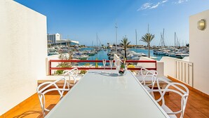 Una terraza con mesa y sillas con vista a un puerto deportivo y barcos.