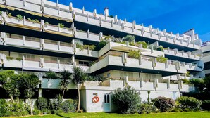 Un edificio de varios pisos con balcones, algunos con plantas.