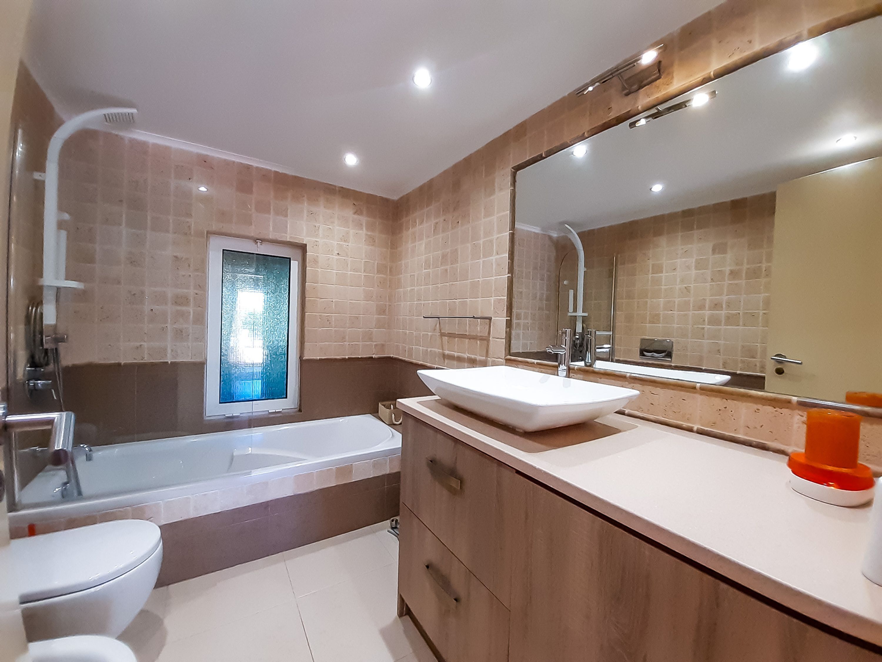 Un baño moderno con bañera, un espejo grande y un lavamanos.