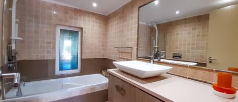 Un baño moderno con bañera, un espejo grande y un lavamanos.