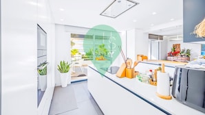 A modern kitchen with white cabinetry, a built-in oven, and a countertop with various kitchen tools and appliances. - Ref gio Sereno Marina T2 Hsrentals Vilamarina (Loulé)