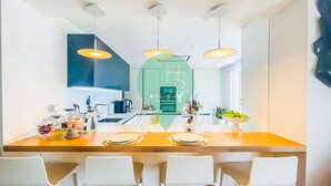 A modern kitchen with a central island, white chairs, and pendant lighting. - Ref gio Sereno Marina T2 Hsrentals Vilamarina (Loulé)