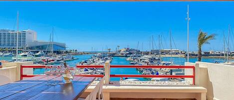 A marina with boats, a building in the background, and a table with chairs in the foreground.