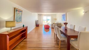 A spacious dining area with a wooden table and chairs, a red bean bag, and artwork on the walls. - Que Sonho Vista Marina T2 Hsrentals Vilamarina (Loulé)