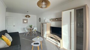 Una sala de estar moderna con sofá, mesa de comedor, televisor y mueble.