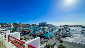 Un port de plaisance où sont amarrés de nombreux bateaux, un grand bâtiment d’hôtel et un ciel bleu dégagé.