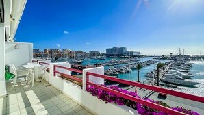 Un balcon avec vue sur une marina et des bâtiments en arrière-plan.