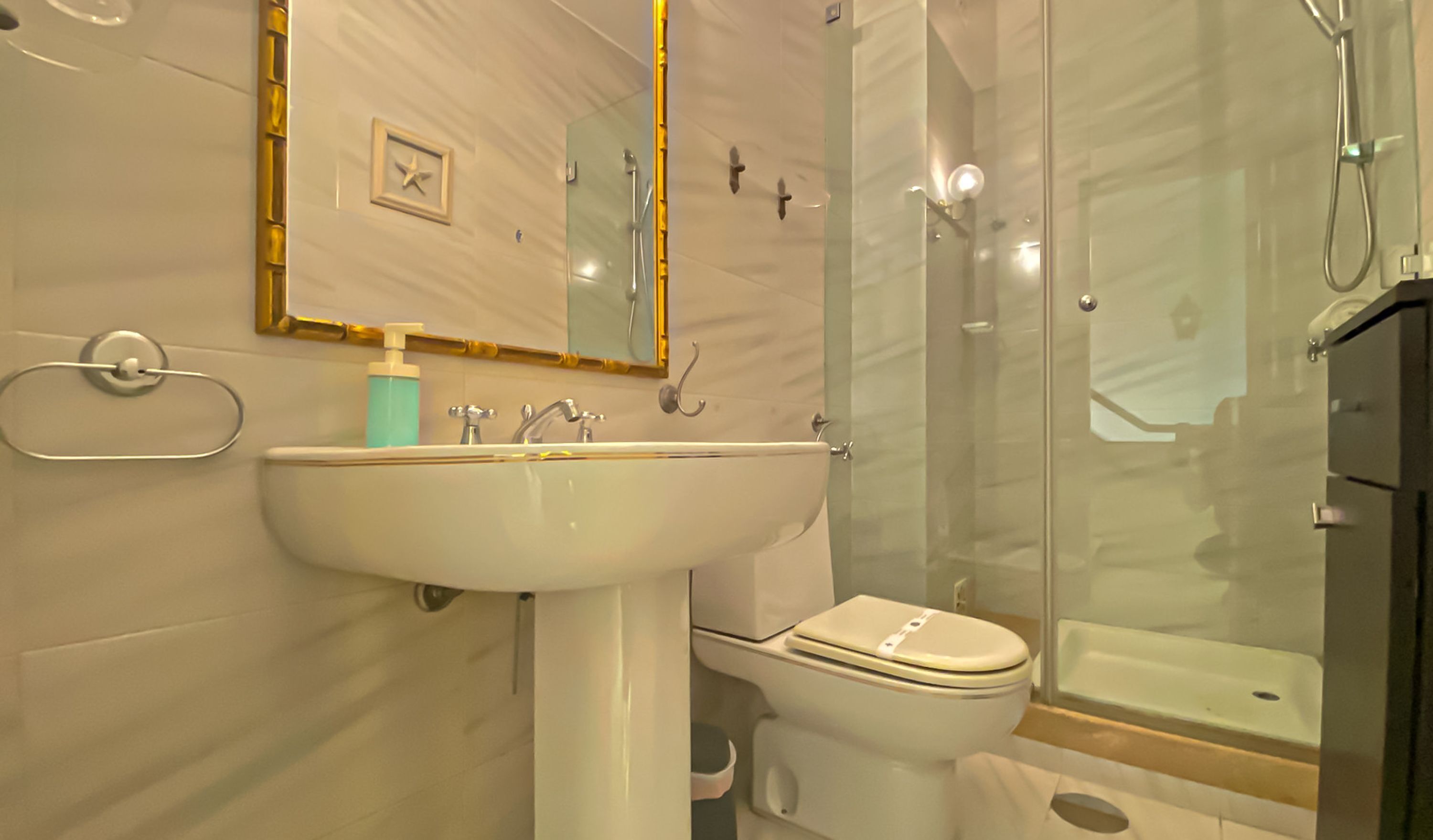 A bathroom with a white sink, toilet, and glass-enclosed shower.