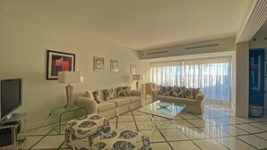 A modern living room with a sofa set, a glass coffee table, and a television. - Intemporal Duplex Marina T2 Hsrentals Vilamoura (Loulé)