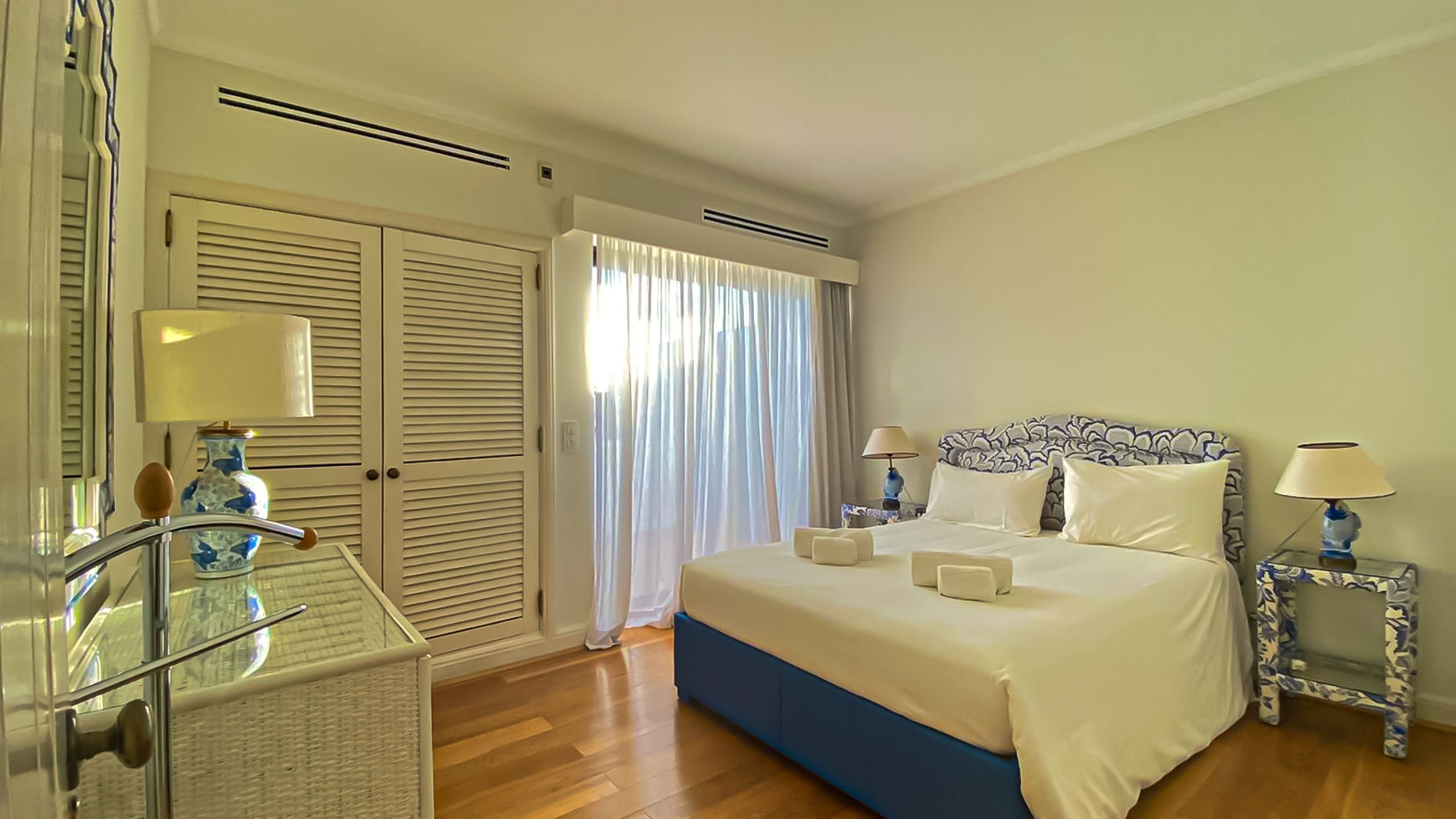 Una habitación de hotel con cama, mesitas de noche, armario y ventana con cortinas.