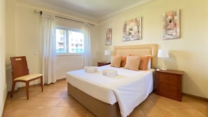 A hotel room with a large bed, two bedside tables, a chair, and artwork on the walls. - Marina Sol T3 Hsrentals Vilamoura (Loulé)