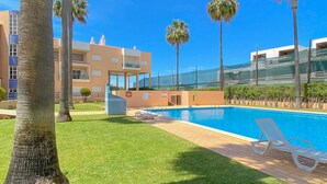 A swimming pool with lounge chairs, palm trees, and a building with balconies. - Marina Sol T3 Hsrentals Vilamoura (Loulé)