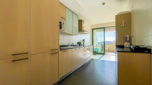 A modern kitchen with light wood cabinets, a stainless steel sink, and a view to the outside. - Aquamar Sunset T2 Hsrentals Marina Vilamoura (Loulé)