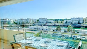 A dining area with a table set for four, overlooking a marina with boats and buildings. - Aquamar Sunset T2 Hsrentals Marina Vilamoura (Loulé)