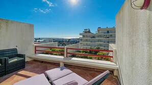 Terraço no telhado com vista para a paisagem urbana, corrimão vermelho e área de estar com almofadas.