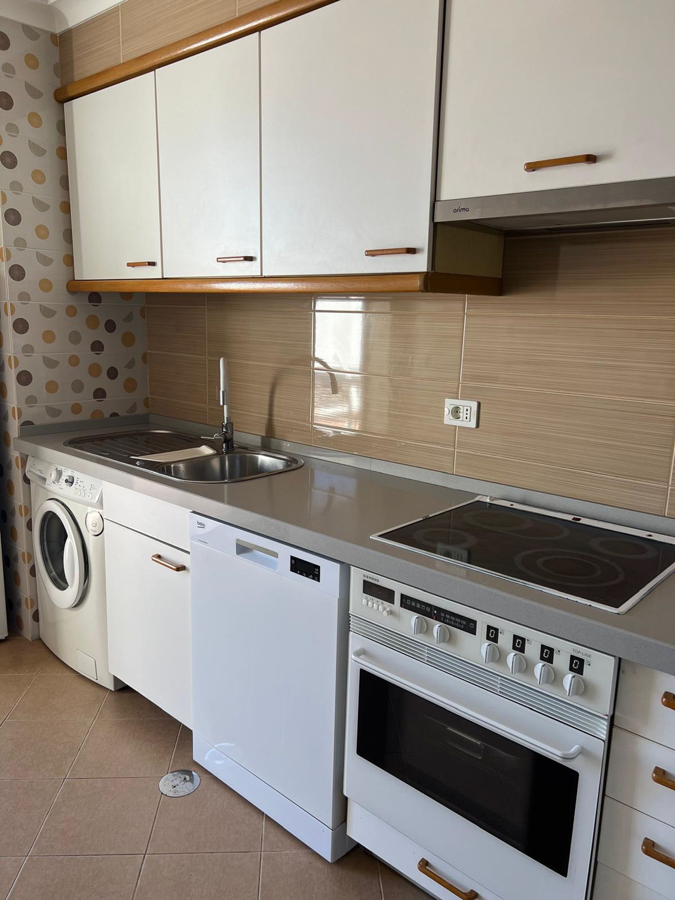 Une cuisine compacte équipée d’un lave-linge, d’un lave-vaisselle, d’une cuisinière et d’un évier.