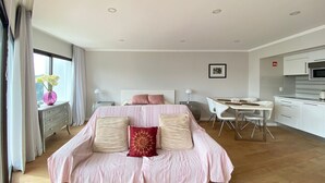 A modern bedroom with a large bed, bedside tables, a desk, and a kitchenette. - Est dio T nis Golf Mar Hsrentals Vilamoura (Loulé)