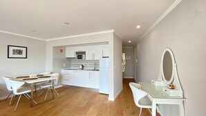 A compact living space with a kitchenette, a dining area with a glass table, and a small vanity with a mirror. - Est dio T nis Golf Mar Hsrentals Vilamoura (Loulé)