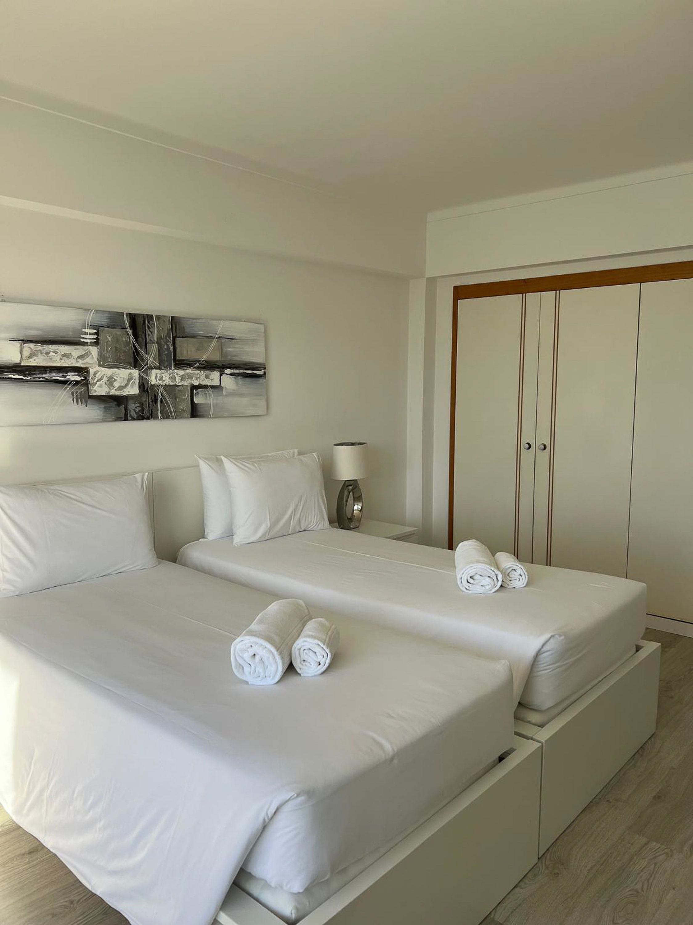 Une chambre d’hôtel avec deux lits, un tableau au mur, une lampe et une armoire.