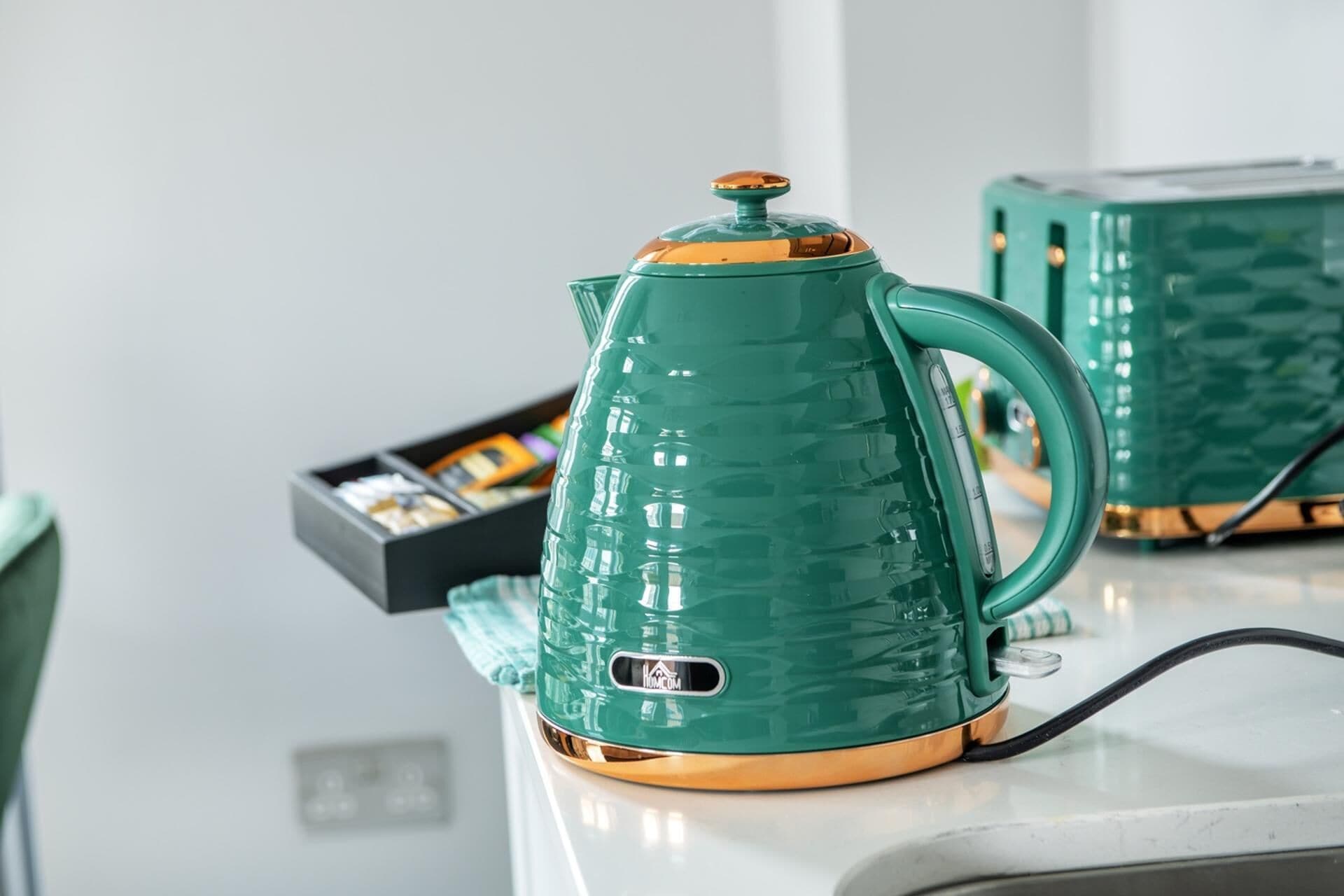 Een groene elektrische waterkoker op een aanrecht, met een doosje theezakjes op de achtergrond.