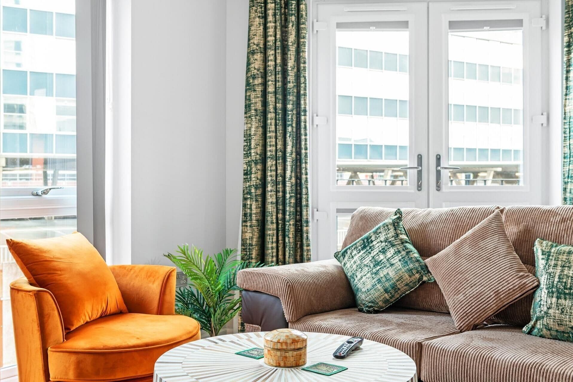 Ein modernes Wohnzimmer mit einer Couch, einem Sessel, einem Couchtisch und Vorhängen.