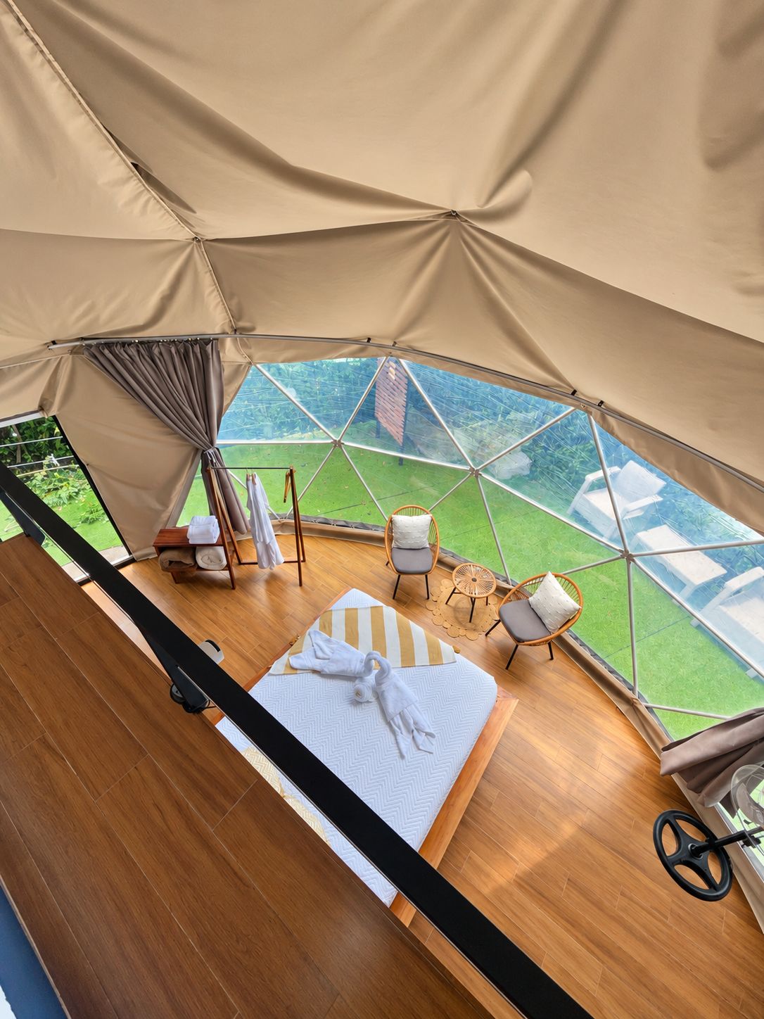 Alojamiento con tienda que incluye cama, sillas y vistas a un paisaje verde.