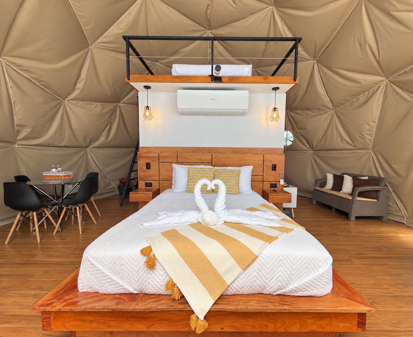 Une chambre aménagée sous une tente, comprenant un lit, un bureau, une chaise et un canapé.