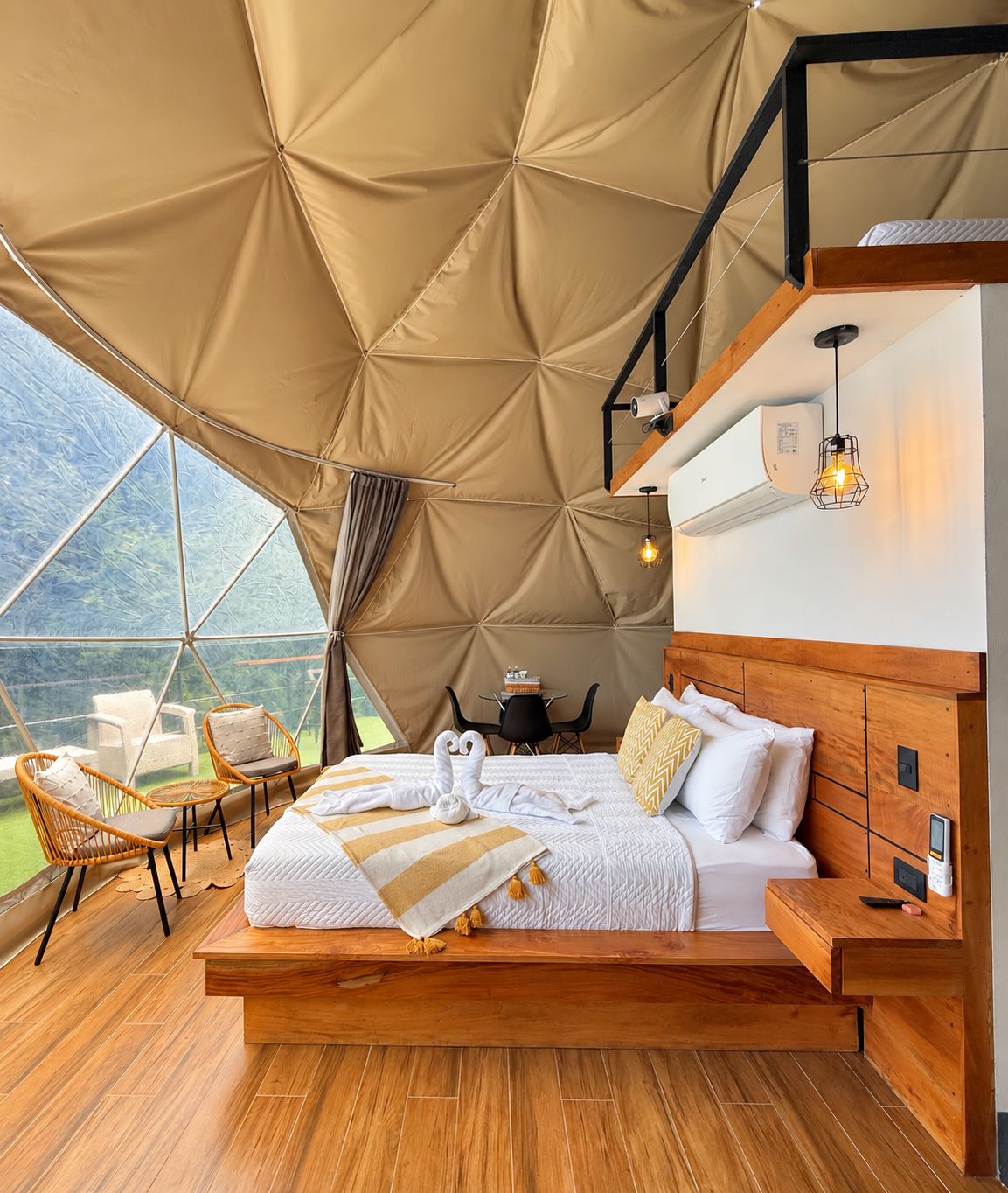 Amplia habitación con tienda de campaña, una cama grande, suelo de madera y vistas al exterior.