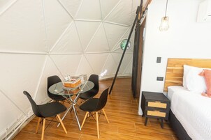 A compact room with a bed, a small table with chairs, and a tent-like structure in the background.