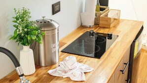 A kitchen with a stainless steel sink, wooden countertop, and a built-in stove. - Macas Moon Glamping (Sierra)
