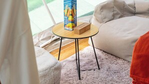 Ein gemütliches Zimmer mit Blick auf Grünflächen, ein kleiner runder Tisch mit einer Schachtel, ein weißes Sofa und ein flauschiger Teppich.