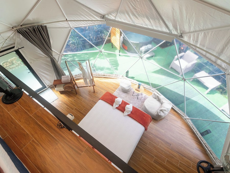 Habitación con tienda de campaña, una cama, un ventilador y vistas a un campo verde.