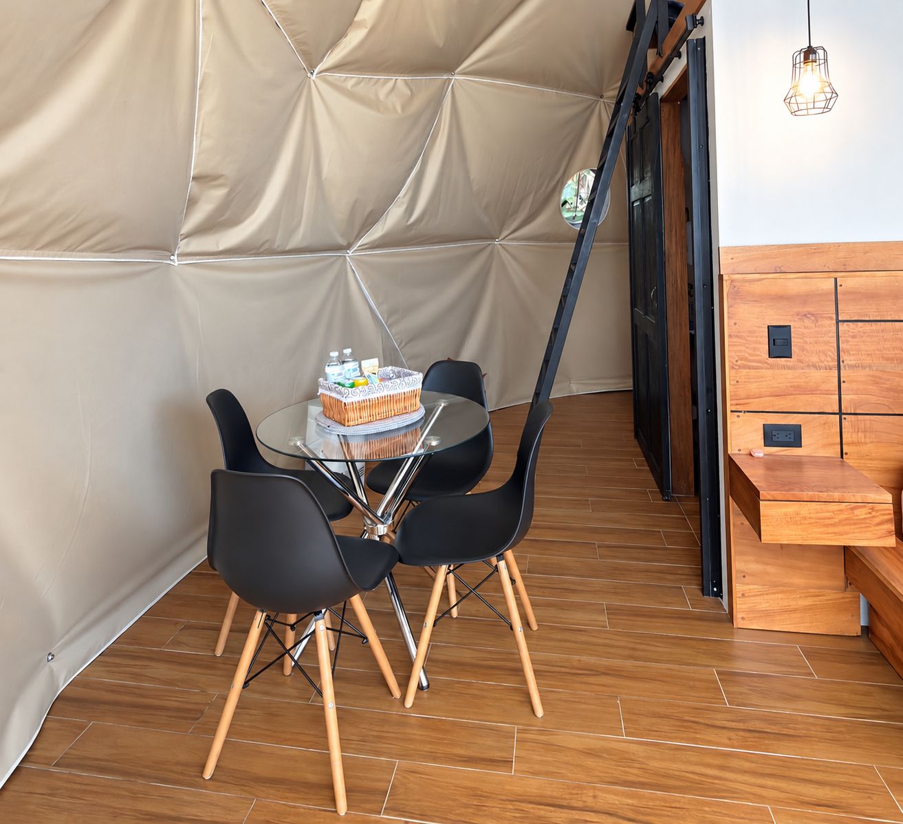 A room with a table and chairs, a wooden bench, and a tent-like structure.