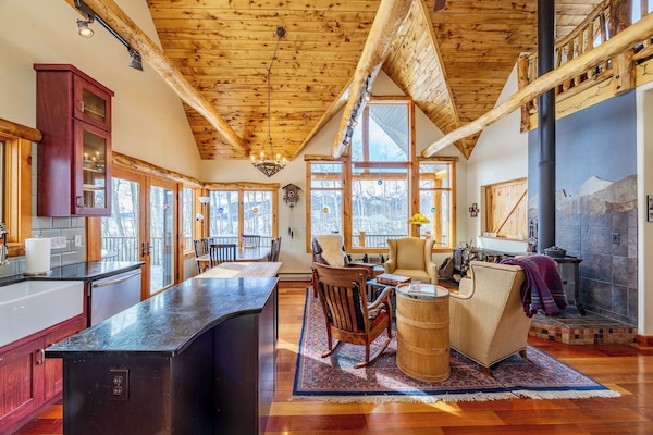 Soaring ceilings, log beams, and panoramic windows define the Aspen Treehouse living space — designed to bring the outdoors in.