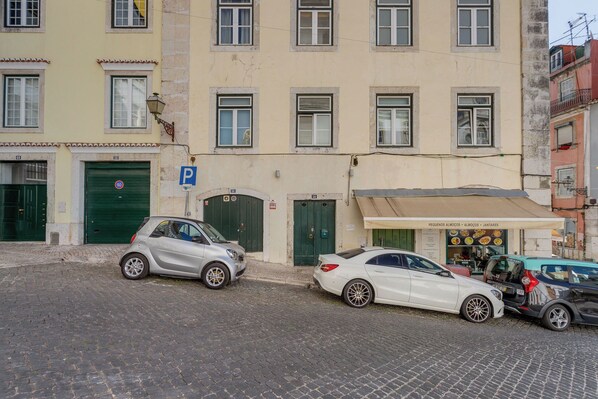 Eine Straße mit parkenden Autos, ein Gebäude mit einer grünen Tür und einem Schild für ein Restaurant.