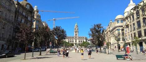A public square with historic buildings, a prominent clock tower, and a construction crane in the background.