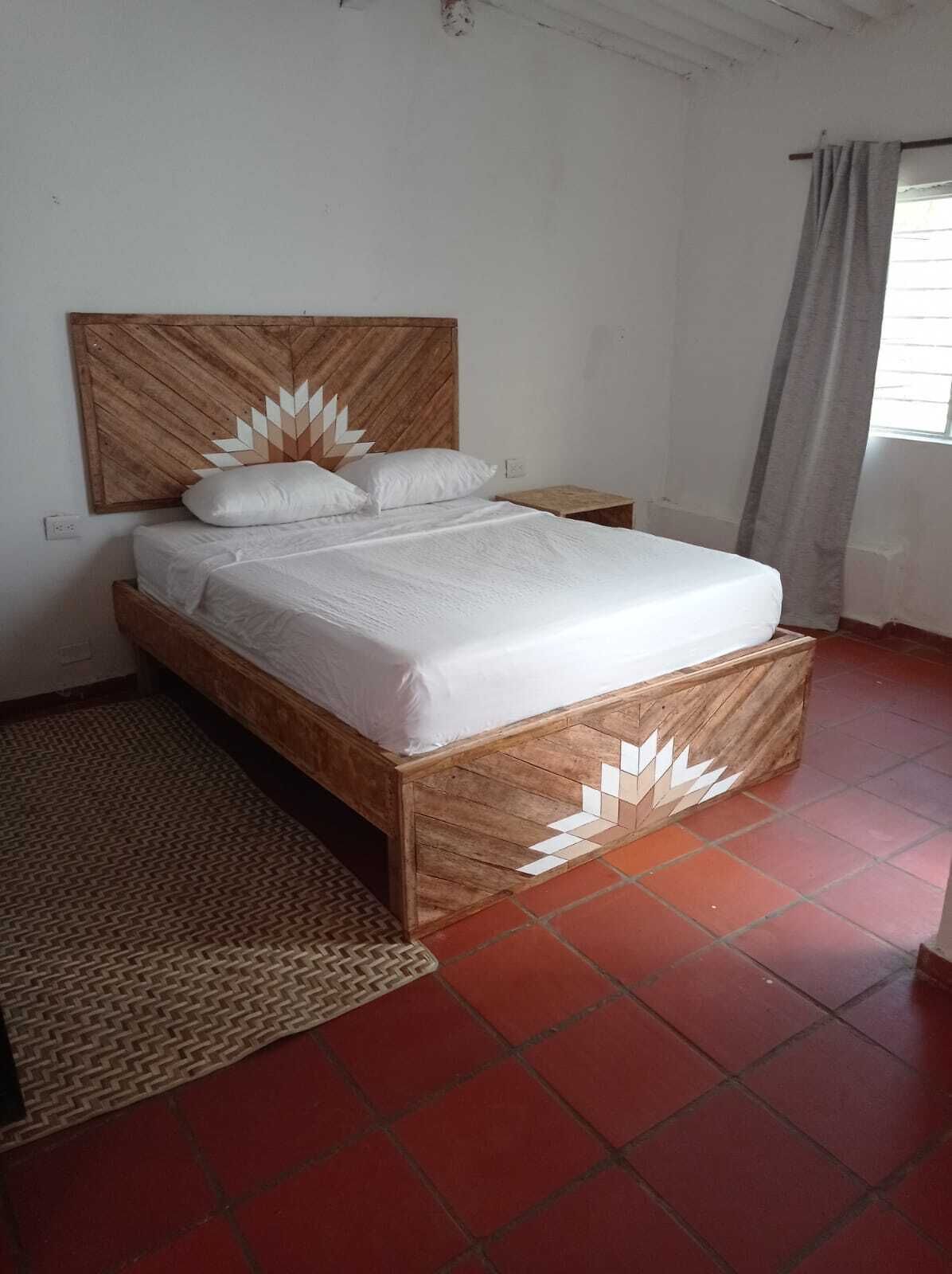 A single-bed room with a wooden headboard, white bedding, and a patterned rug.